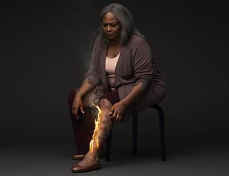 A female model with simulated prurigo nodularis reaches down to scratch raised firm nodules on her lower leg due to the severe itch she suffers